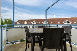 En balkon med et bord og stole, der kigger ud over række af huse med røde tage.