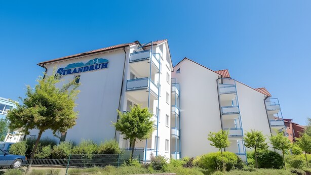 Un edifici de diverses plantes amb balcons, un rètol que diu 'Grandruth' i un cel blau clar.