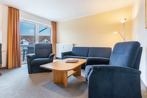 En moderne stue med sofa, lænestole, sofabord og gulvlampe.