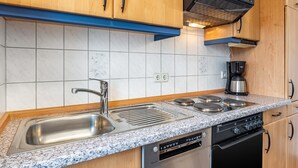 Cozinha moderna com pia de aço inoxidável, forno duplo e lava-louças embutida.