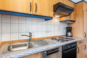 Una cocina moderna con un lavamanos de acero inoxidable, horno doble y lavavajillas empotrado.