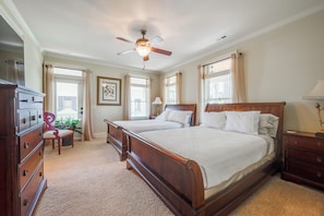A bedroom with two beds, a ceiling fan, a dresser, a chair, and a window with curtains.