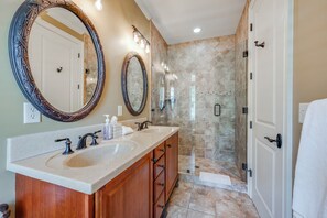 Une salle de bain avec deux lavabos, un grand miroir et un espace douche.