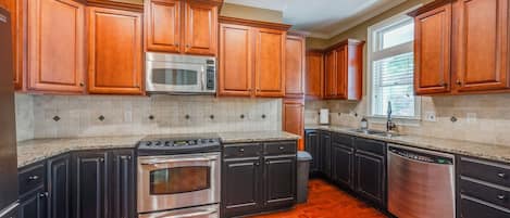 A kitchen with wooden cabinets, a stainless steel microwave, a dishwasher, and a stove.