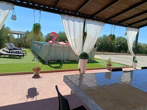 A covered outdoor area with a pool, lounge chairs, and potted plants. - Room in Villa with Pool, Wi-Fi and Air Conditioning (Solarino)