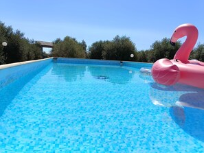 A clear blue pool with a pink flamingo float. - Room in Villa with Pool, Wi-Fi and Air Conditioning (Solarino)