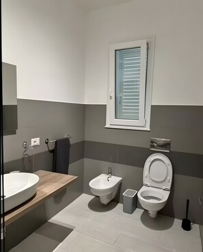 A modern bathroom with a large sink, bidet, toilet, and a window with blinds. - Room in Villa with Pool, Wi-Fi and Air Conditioning (Solarino)