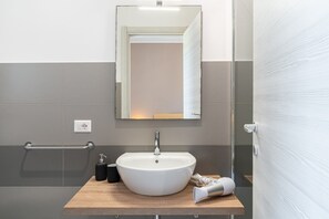 A bathroom with a white sink, a mirror, a towel rack, and a wooden vanity. - Bedroom in Villa with Pool, Wi-Fi and Air Conditioning (Solarino)
