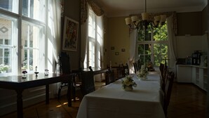 A dining area with a long table, chairs, a chandelier, and large windows with curtains. - Landsitz Kammerburg - Villa (Lorch)