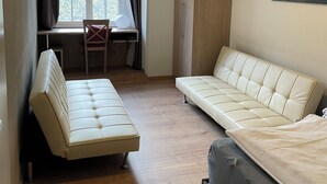 A room with a sofa, a chair, a cabinet, a radiator, and a window with curtains. - Landsitz Kammerburg - Villa (Lorch)