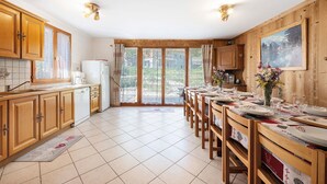 Eine Küche mit Holzausstattung, einem Kühlschrank und einem Essbereich mit Tisch für vier Personen.