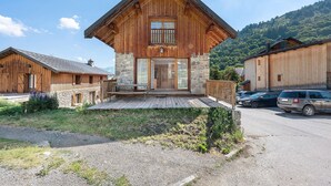 Eine Holzhütte mit Steinfundament, einem Balkon und Blick auf eine gebirgige Landschaft.