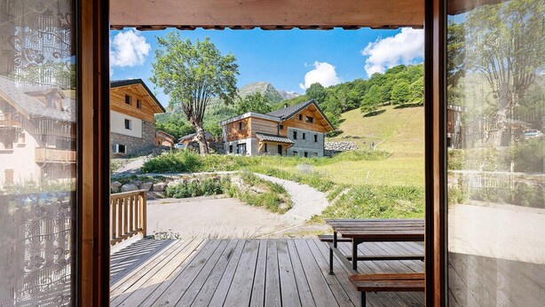 Eine Holzterrasse mit Blick auf eine Hügelkuppe und Gebäude.