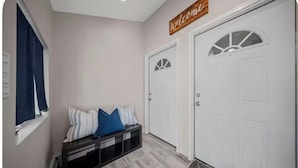 A hallway with a bench, two doors, and a welcome sign.