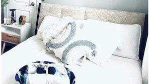 A bedroom with a bed, pillows, a bedside table, and two wall-mounted artworks.