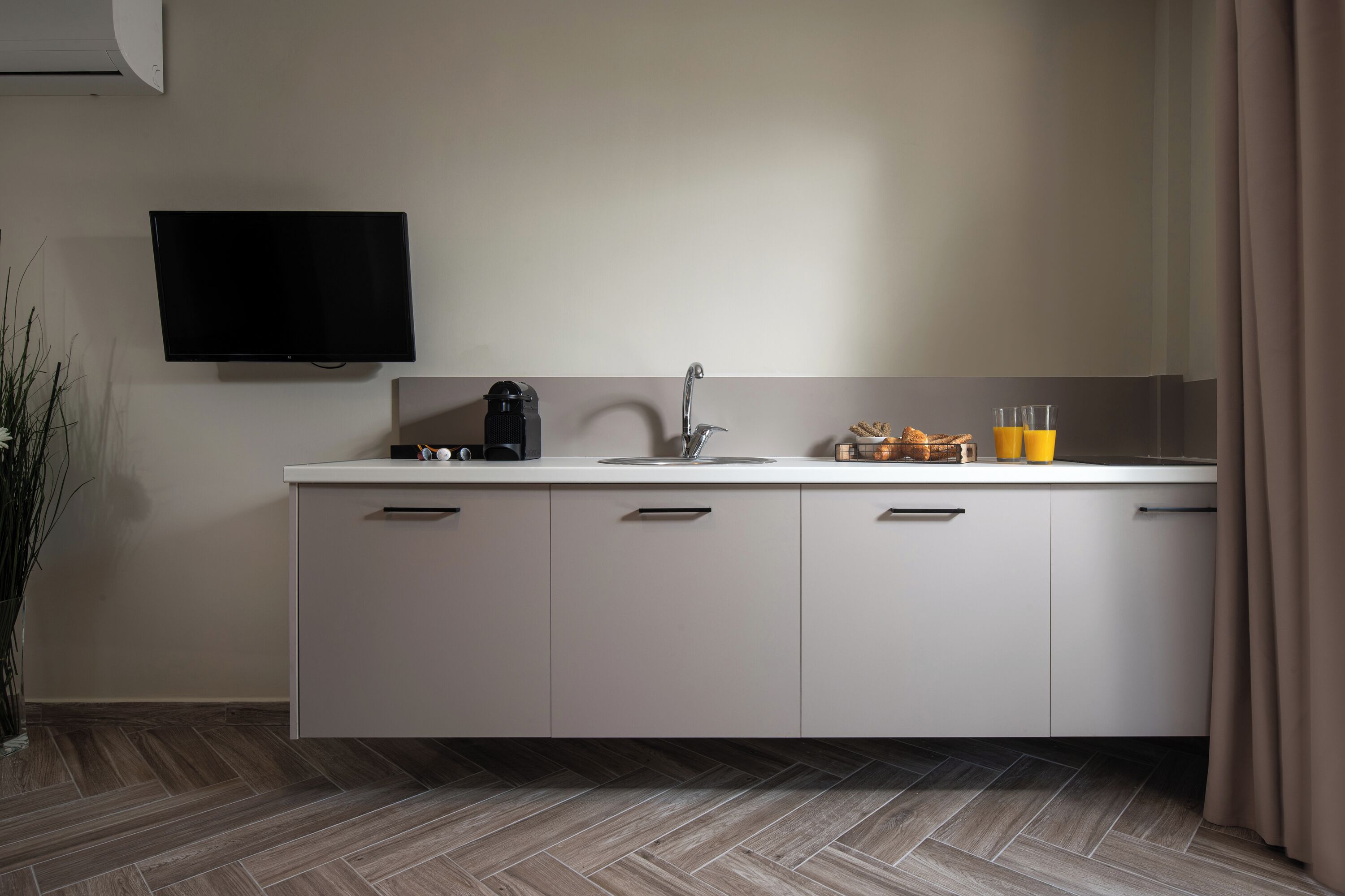 A modern kitchen with a flat-screen TV, a coffee maker, and a sink.
