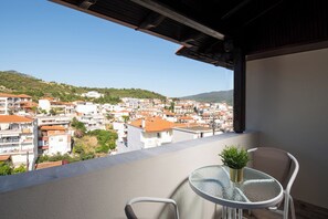 Un balcon avec une table et des chaises, donnant sur un quartier résidentiel densément peuplé, caractérisé par des toits recouverts de tuiles rouges.