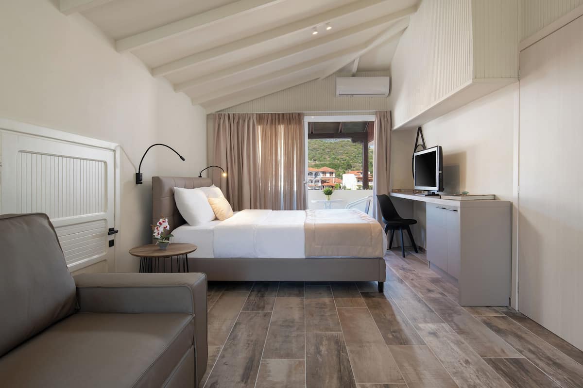 Une chambre à coucher avec un lit, un bureau, une chaise, un canapé et un téléviseur.
