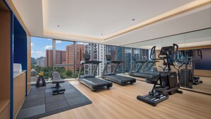 A modern gym with treadmills, elliptical machines, and free weights, large windows with a city view. - Holiday Inn Express Beijing Haidian Suzhouqiao by IHG (Beijing)