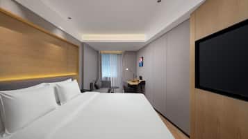 A hotel room with a large bed, a desk, a chair, a TV, and a window with curtains.