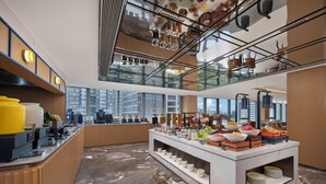A modern hotel lobby with a high ceiling, a glass railing, and a buffet area with various food items. - Holiday Inn Express Beijing Haidian Suzhouqiao by IHG (Beijing)