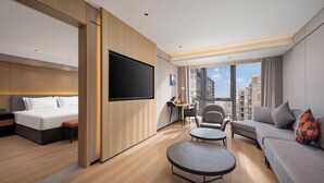 A modern hotel room with a bed, sofa, armchair, small table, and a TV. - Holiday Inn Express Beijing Haidian Suzhouqiao by IHG (Beijing)