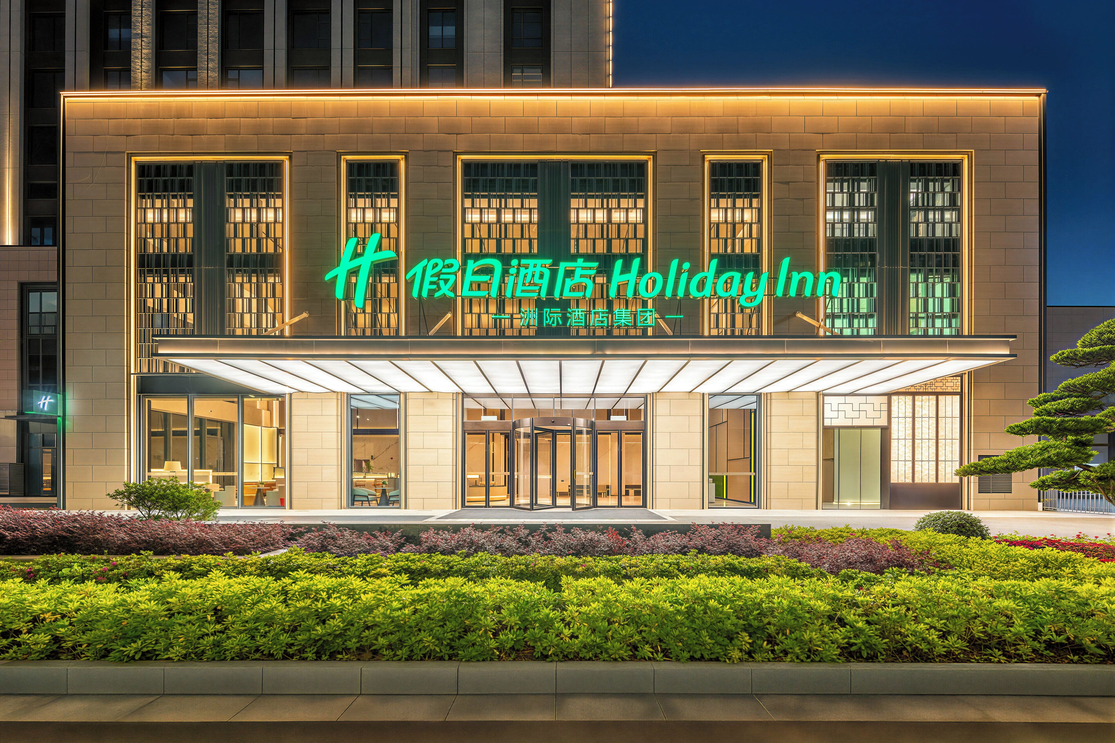A modern hotel with a prominent sign, large windows, and a covered entrance.