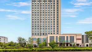 En hög hotellbyggnad med en modern design, som kännetecknas av en tydlig skylt med texten ”Holiday Inn”.