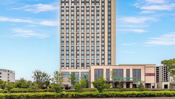 Un grand immeuble d’hôtel au design moderne, avec une enseigne « Holiday Inn » bien visible.