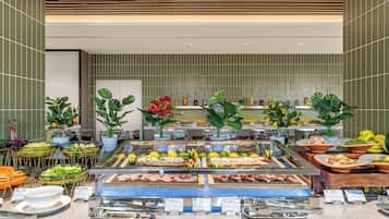 Un bufé con diversas opciones de comida, como carnes, ensaladas y frutas.