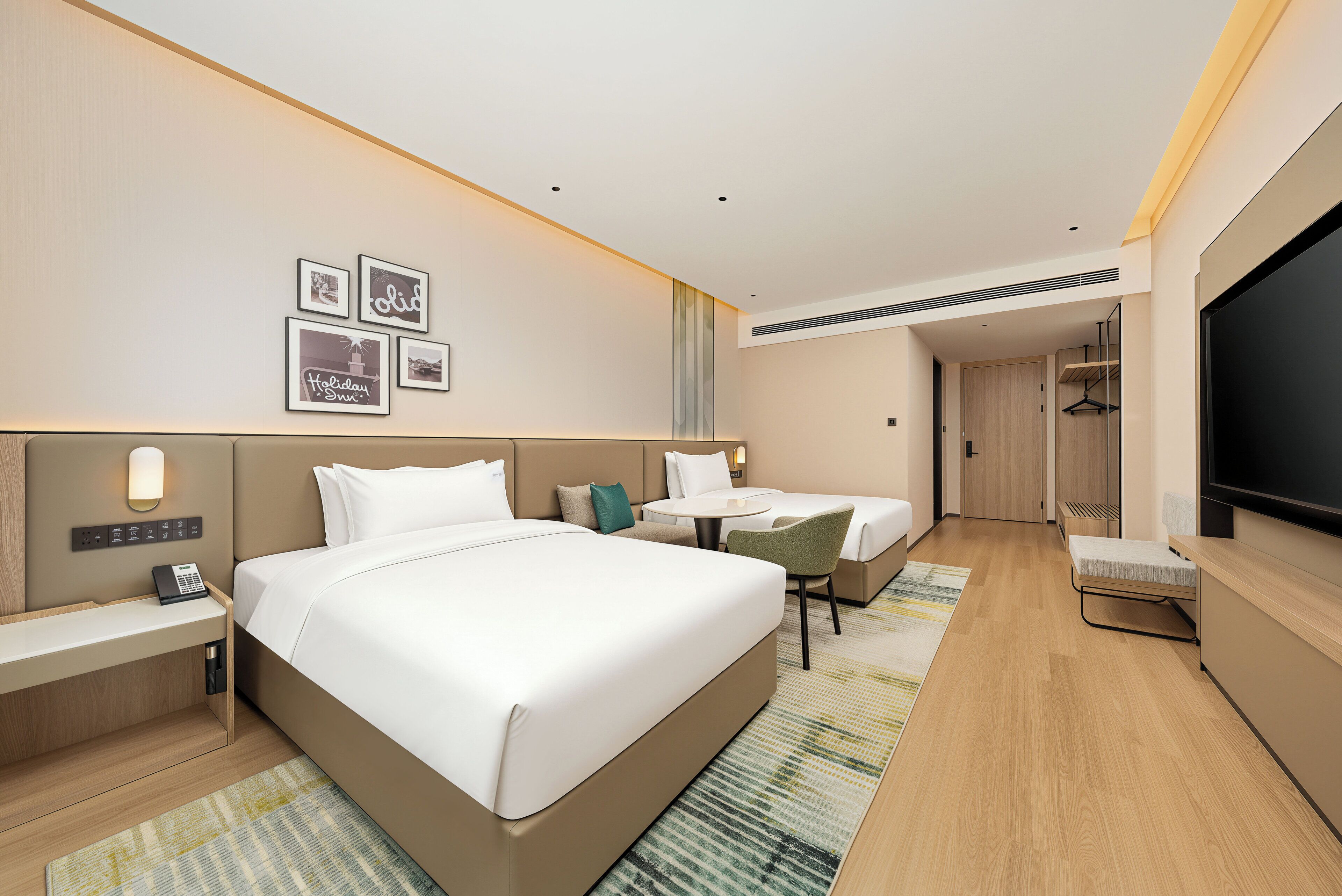 Habitación de hotel con una cama grande, un escritorio, una silla, un televisor y una lámpara fijada a la pared.