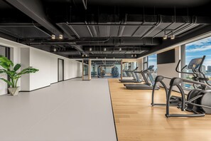 A gym with treadmills, exercise equipment, and a large window with a city view. - Holiday Inn Qidong Lvsi Port by IHG (Nantong)