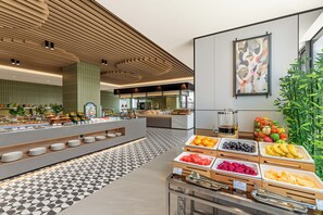 A buffet area with various food options, a coffee station, and a large abstract painting on the wall.