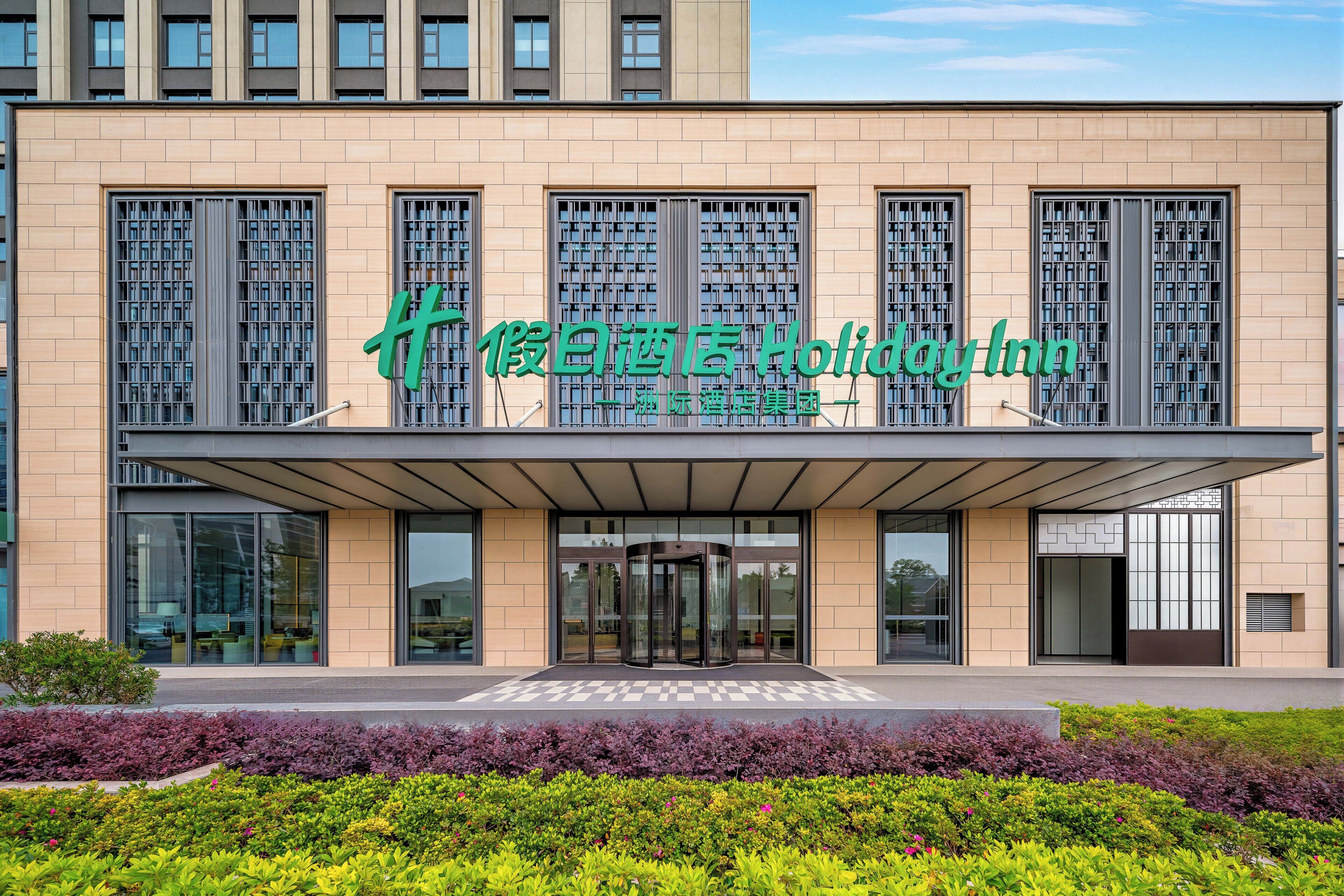 A modern building with a prominent green sign for a hotel.