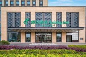 A modern building with a prominent green sign for a hotel.
