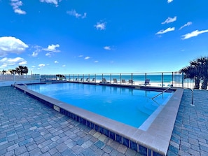 Una piscina con vistas a la playa y palmeras.