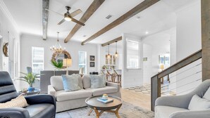 A spacious living room with a sofa, armchairs, a coffee table, and a staircase.