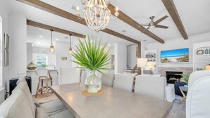 A modern interior with a dining area, a chandelier, ceiling fans, and a fireplace.