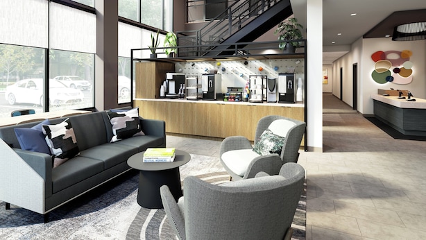 A modern hotel lobby with a sofa, chairs, a coffee bar, and a staircase. - Atwell Suites Liberty - Kansas City East by IHG (Liberty)