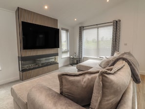 Ein Wohnzimmer mit Flachbildfernseher, einer Couch und einem Kamin.