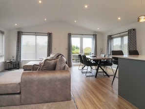 Una sala moderna con sofá, mesa de comedor, sillas y una zona de cocina con mostrador.
