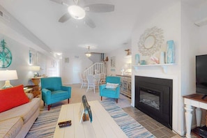 A living room with a fireplace, a ceiling fan, and a staircase leading to another level. - Mallard Lakes - 158 Cardinal Ln (Selbyville)
