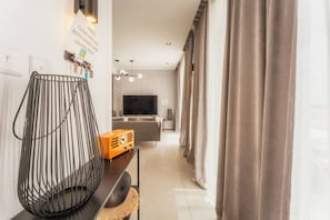 Un salon moderne avec un téléviseur, un canapé et une chaise décorative en métal.