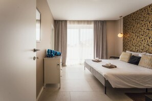 Une chambre d’hôtel comprenant un lit, un bureau, une chaise, une armoire et une fenêtre avec des rideaux.