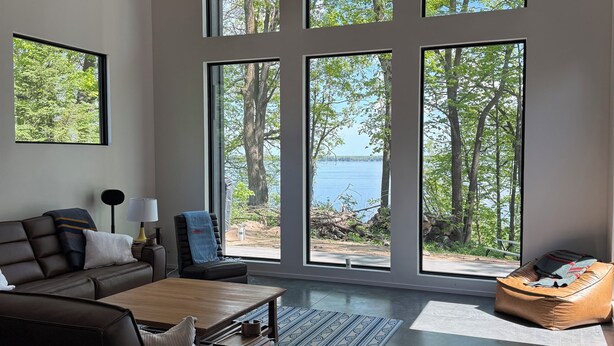 Una sala de estar moderna con un ventanal grande, un sofá, una mesita de centro y un sillón informal.