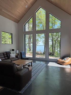 Una sala de estar moderna con un ventanal grande, un sofá, una mesita de centro y un sillón informal.
