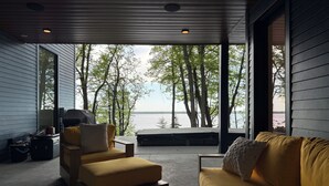 Un espacio de estar al aire libre cubierto con vistas a un lago y árboles.