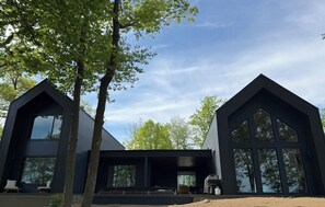 Ett modernt hus i två våningar med en stor veranda på framsidan, stora fönster och en symmetrisk design.