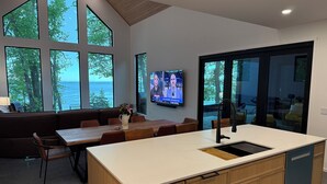 Cocina moderna con una isla grande, comedor con vistas y un televisor en la pared.