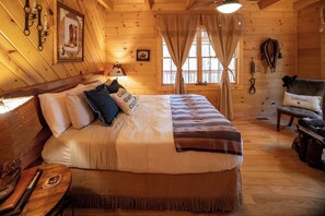 Ein Holzhütten-Zimmer mit einem Bett, einer Bank, einem Tisch und einem an der Wand befestigten Kleiderhaken.